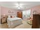 Cozy bedroom features pink walls, a ceiling fan, and a comfortable sitting area by the window at 4875 Rivercliff Sw Trce, Lilburn, GA 30047
