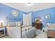 Bright blue bedroom features a brass bed frame, an area rug, and a chair with throw pillows at 4875 Rivercliff Sw Trce, Lilburn, GA 30047