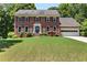 Traditional brick home features a manicured lawn, charming blue door, and attached two-car garage at 4875 Rivercliff Sw Trce, Lilburn, GA 30047