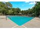 Large in ground swimming pool surrounded by trees and chairs with an additional covered seating area at 4875 Rivercliff Sw Trce, Lilburn, GA 30047