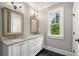 Bright bathroom featuring double vanities with marble countertops and contrasting black tile floor at 1338 Iverson Ne St, Atlanta, GA 30307