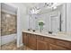 Bright bathroom featuring a double sink vanity with wood cabinets, large mirror, and tiled shower and floors at 120 Daniel Creek Ln, Sugar Hill, GA 30518
