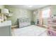 Well-lit Bedroom with a gray crib, hardwood floors, and decorative pink accents at 1035 Cornish Mountain Church Rd, Oxford, GA 30054