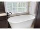 Close-up of a freestanding tub, dark wood cabinets, and a large window at 1850 Kirkmont Nw Dr, Marietta, GA 30064