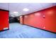 Spacious carpeted basement with red accent wall, bright lighting, and ample room for various activities at 7090 Valley Landing Ct, Cumming, GA 30041