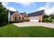 Traditional brick home featuring a two-car garage, manicured lawn, and lush landscaping on a sunny day at 7090 Valley Landing Ct, Cumming, GA 30041
