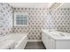 Traditional bathroom featuring a tub, double sink vanity and patterned wallpaper at 2379 Fallbrook Ct, Duluth, GA 30096