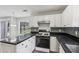 Bright kitchen with white cabinetry, dark countertops and backsplash, stainless appliances and laminate flooring at 2379 Fallbrook Ct, Duluth, GA 30096