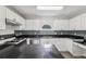 Bright kitchen featuring white cabinetry, dark countertops and backsplash, and stainless-steel appliances at 2379 Fallbrook Ct, Duluth, GA 30096
