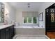 Elegant bathroom featuring a soaking tub, marble surround, and a vanity with ample counter space and storage at 510 Heards Ferry Rd, Atlanta, GA 30328