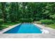 This backyard includes a private in-ground swimming pool surrounded by lush green trees and manicured landscaping at 510 Heards Ferry Rd, Atlanta, GA 30328