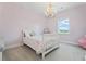 A charming bedroom with a whimsical chandelier and a window view offers a cozy retreat at 5315 Hendrix Rd, Cumming, GA 30040