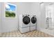 Bright laundry room featuring modern washer and dryer, complemented by patterned tile floor and window view at 5315 Hendrix Rd, Cumming, GA 30040