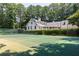 Private tennis court on the property, surrounded by lush trees, with the house in the background at 1016 Old Powers Ferry Rd, Atlanta, GA 30327