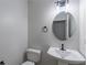 Half bathroom with a pedestal sink, toilet, oval mirror, and modern light fixture at 3807 Lance Bluff Ct, Duluth, GA 30097