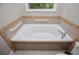 Elegant bathtub with neutral tile surround, grab bars, and bright window at 8040 Banks Mill Rd, Douglasville, GA 30135