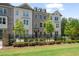 Attractive three-story townhome with stone and brick exterior, manicured lawn and landscaping, and a dark metal fence at 102 Brackley Dr, Cumming, GA 30040