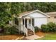 The exterior of a cozy white home with a manicured front yard and lush green foliage, nestled in a serene setting at 1947 Main St, Atlanta, GA 30318