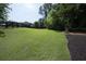 Expansive backyard featuring lush green lawn, trees, and a dark wooden fence line along the back perimeter at 1895 Henley Way, Alpharetta, GA 30009