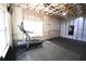 Finished basement area with a treadmill, dark floors, windows, and a ceiling fan at 1895 Henley Way, Alpharetta, GA 30009