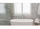 Bright bathroom featuring soaking tub with marble accent wall and white plantation shutters at 1895 Henley Way, Alpharetta, GA 30009