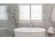 Freestanding bathtub in a luxurious bathroom with a decorative tile wall and modern fixtures at 1895 Henley Way, Alpharetta, GA 30009