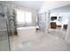 Bright bathroom featuring soaking tub with a marble accent wall, glass shower, and entrance to the living room at 1895 Henley Way, Alpharetta, GA 30009