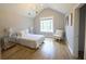 Bright bedroom featuring a vaulted ceiling, gold chandelier, and light hardwood flooring at 1895 Henley Way, Alpharetta, GA 30009