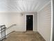 A black front door on a porch with wood flooring, side rails and neutral siding at 3217 Fairington Dr, Lithonia, GA 30038