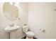 Charming powder room featuring a pedestal sink, toilet, and round mirror with a decorative flower accent at 522 Spring View Dr, Woodstock, GA 30188