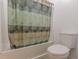 The bathroom features a tub and shower combination with a neutral patterned shower curtain and a white toilet at 1667 Quail Run, Conyers, GA 30094