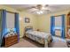 This bedroom has yellow walls and blue curtains framing a window and a wooden ceiling fan at 1667 Quail Run, Conyers, GA 30094