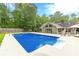 In-ground pool with diving board, surrounded by concrete patio, landscaping, lush trees, and fenced yard at 1667 Quail Run, Conyers, GA 30094