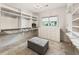 Walk-in closet with custom shelving, drawers, and center ottoman at 625 Wynfield Ct, Roswell, GA 30076