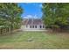 Spacious backyard with a green lawn, mature trees, and a concrete patio with access to the home at 7057 Silver Bend Ovrlk, Austell, GA 30168