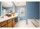 Well-lit bathroom with a double sink vanity, large mirror, soaking tub, and blue accent wall at 7057 Silver Bend Ovrlk, Austell, GA 30168