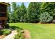 Lush backyard with a green lawn, mature trees, and stone walkway at 141 Olde Heritage Way, Woodstock, GA 30188