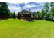 Expansive backyard featuring lush green lawn, mature trees, and a screened porch with outdoor kitchen at 141 Olde Heritage Way, Woodstock, GA 30188
