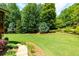 Lush backyard with a green lawn, mature trees, and stone accents at 141 Olde Heritage Way, Woodstock, GA 30188