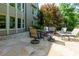 Stone patio with outdoor seating surrounded by lush greenery and a house at 141 Olde Heritage Way, Woodstock, GA 30188
