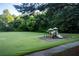 Community playground with a slide and swings, set in a grassy area with mature trees at 141 Olde Heritage Way, Woodstock, GA 30188