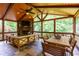 Inviting sunroom with stone fireplace, wood ceiling, exposed beams, and floor-to-ceiling windows with wooded views at 141 Olde Heritage Way, Woodstock, GA 30188