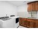 Bright laundry room features white stacked washer and dryer, wood cabinets and white subway tile backsplash at 2775 Club Valley Ct, Jonesboro, GA 30236