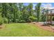 Expansive backyard with lush lawn, bordered by mature trees, and a glimpse of the inviting in-ground pool at 1344 Hamilton Creek Nw Dr, Kennesaw, GA 30152