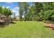 Well-manicured backyard with verdant lawn, bordered by trees and shrubs, offering ample outdoor space at 1344 Hamilton Creek Nw Dr, Kennesaw, GA 30152