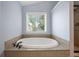 Soaking tub next to window with tiled surround in bathroom at 1344 Hamilton Creek Nw Dr, Kennesaw, GA 30152