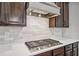 Close-up of a modern gas cooktop with stainless steel range hood and white tile backsplash at 1344 Hamilton Creek Nw Dr, Kennesaw, GA 30152