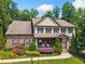 Charming two-story home featuring a stone facade, landscaped yard, and inviting front porch with rocking chairs at 1344 Hamilton Creek Nw Dr, Kennesaw, GA 30152