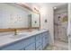 Charming bathroom with double sinks, soft blue cabinets, and a whimsical dinosaur-themed shower curtain at 1452 Crooked Tree Cir, Stone Mountain, GA 30088