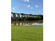 Scenic lake view with homes, green grass, and a beautiful blue sky at 443 Marsh Lake Rd, Lawrenceville, GA 30045